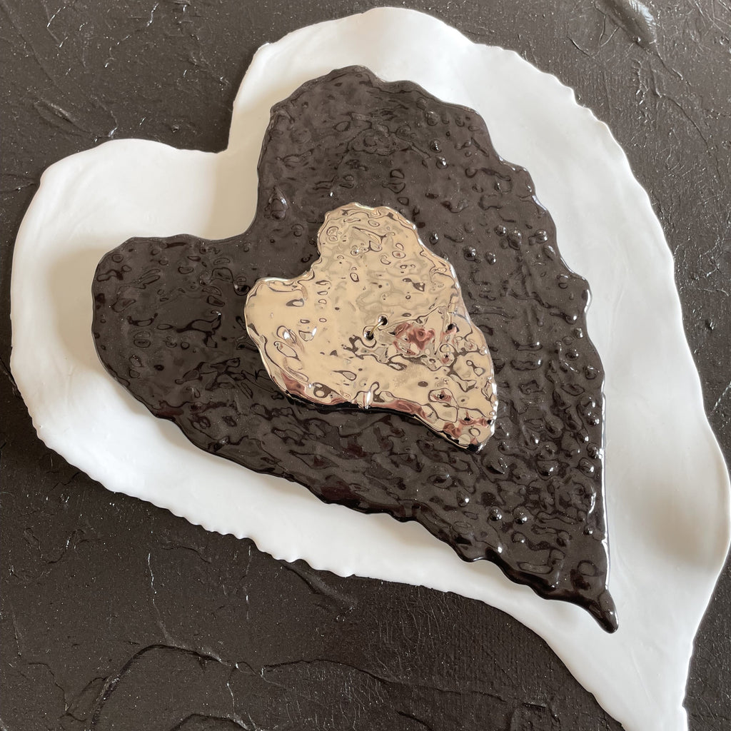 tableau acrylique et éléments en porcelaine. toile représente le coeur de vho . les couleurs sont noir, blanc et platine format paysage dimensions : 50x40